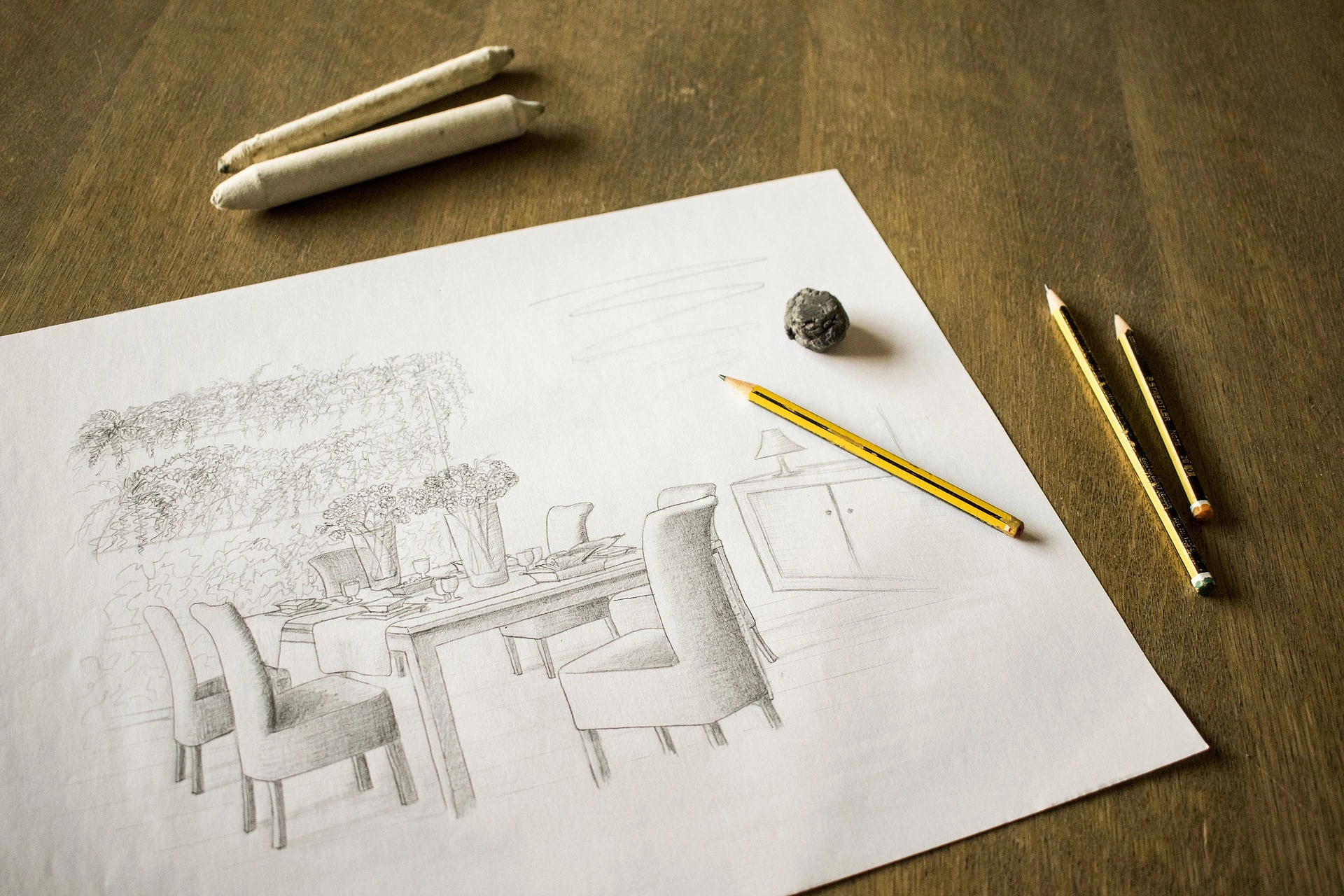 Drawing equipment and a graphite sketch of a dining table and some chairs