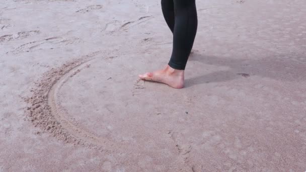608x342 Woman With Bare Feet Drawing Circle On Sand Near Sea Stock Video