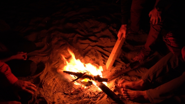 590x332 Man Drawing On Sand With A Log Near The Beach Campfire By Tomasadzke