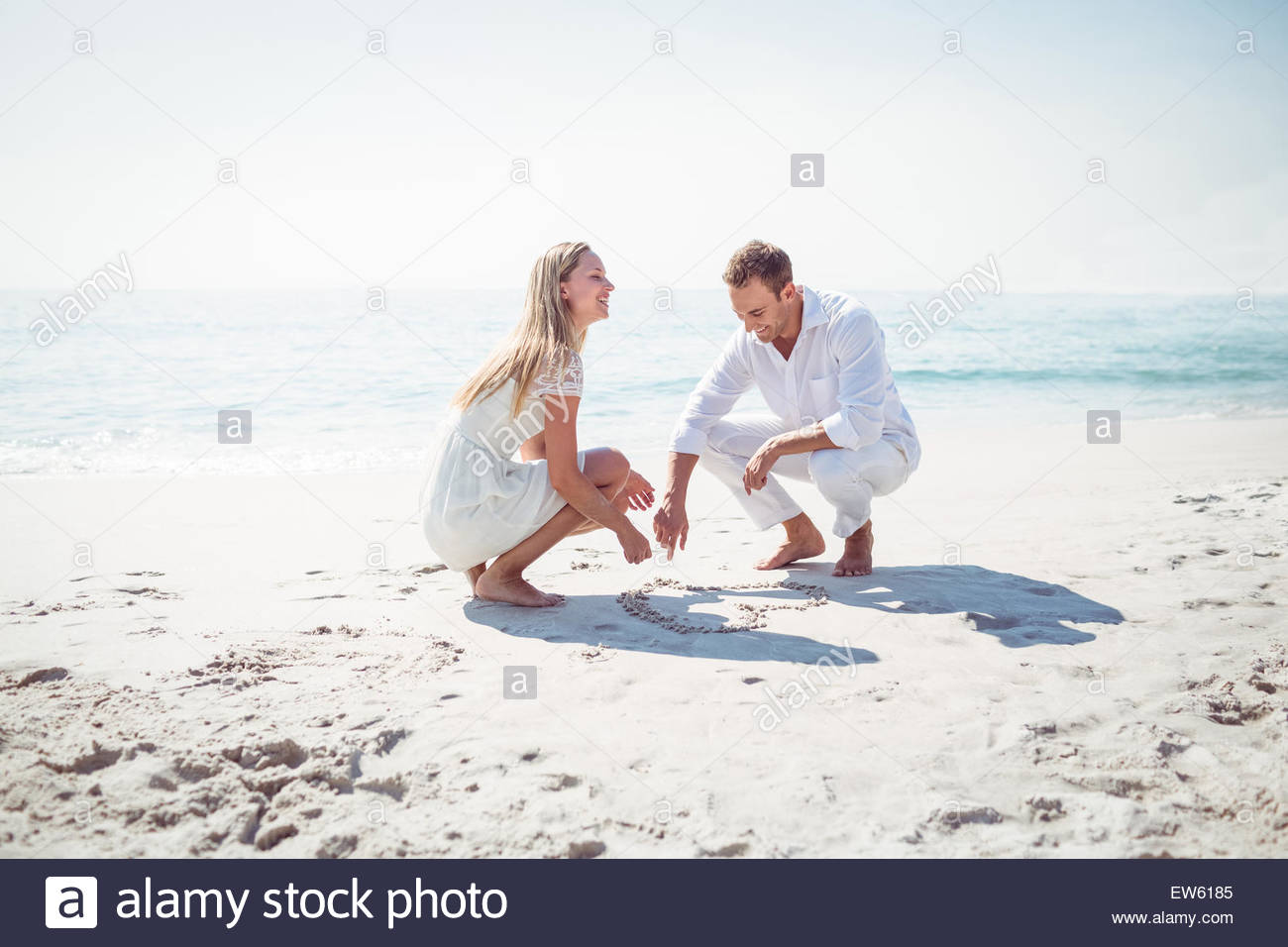 1300x956 Happy Couple Drawing Heart Shape In The Sand Stock Photo, Royalty