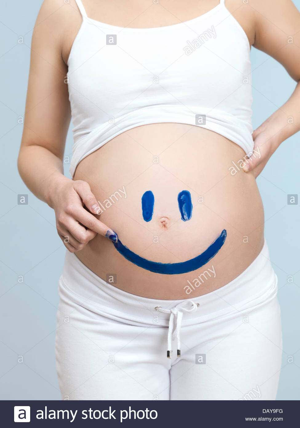975x1390 Pregnant Woman Drawing A Happy Smiley Face On Her Belly Stock